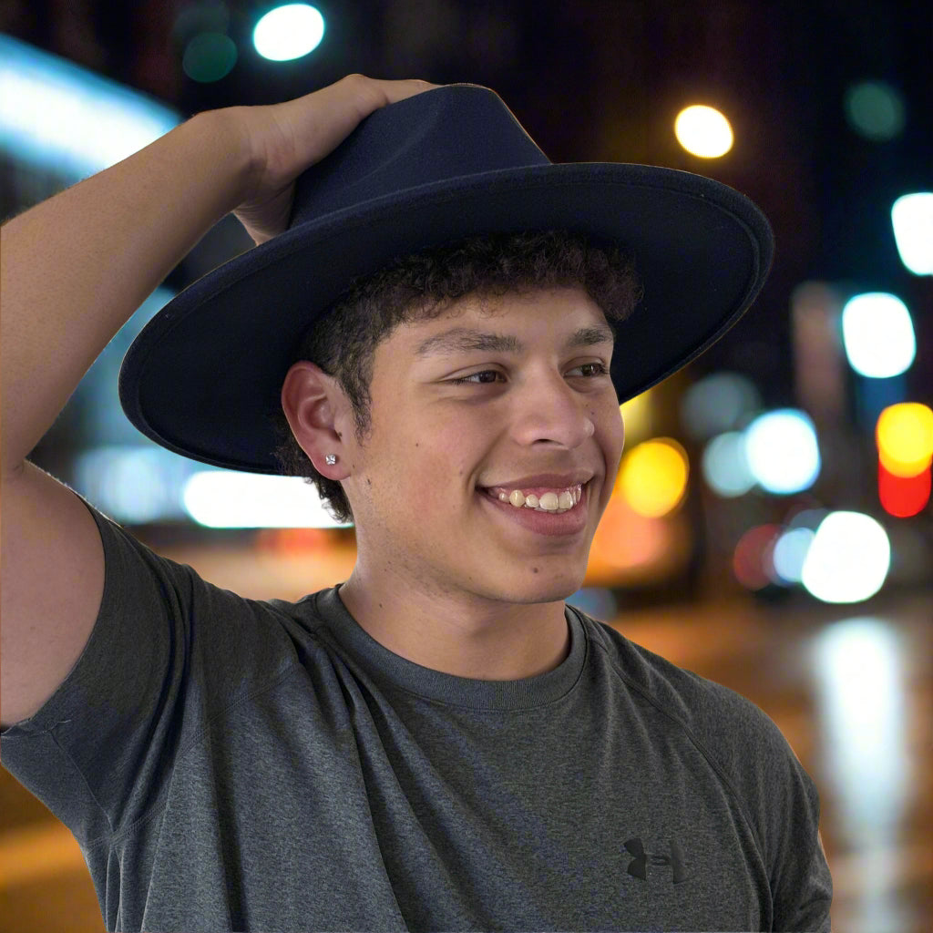 Man holding the brim of a black Dion wide-brim fedora.