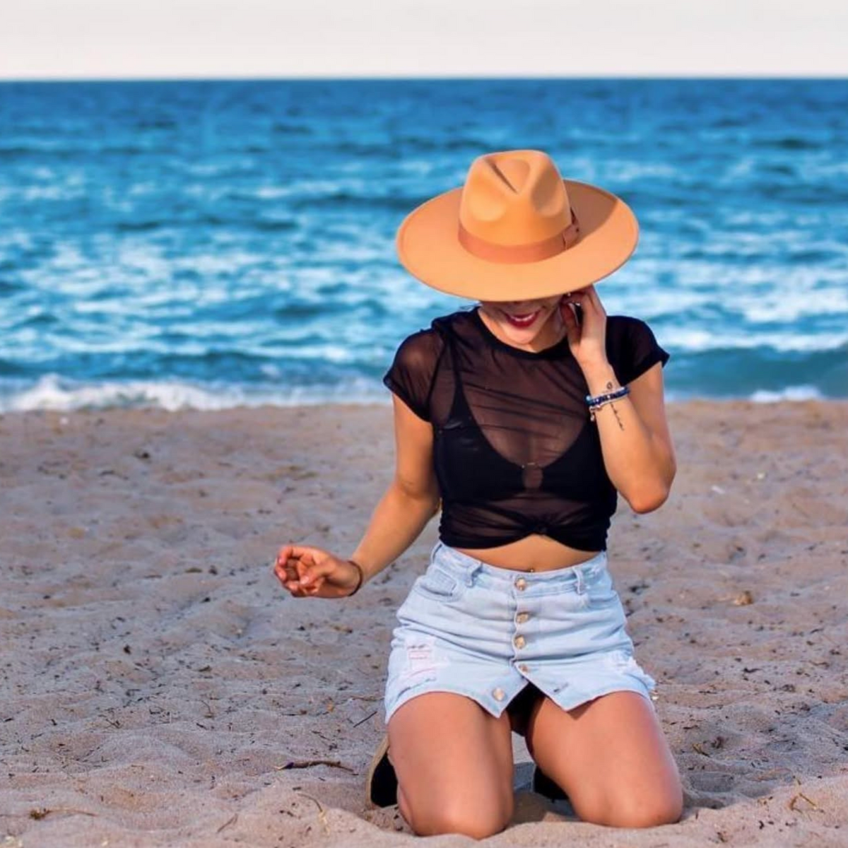 Woman wearing a tan Dion wide-brim fedora at the beach.