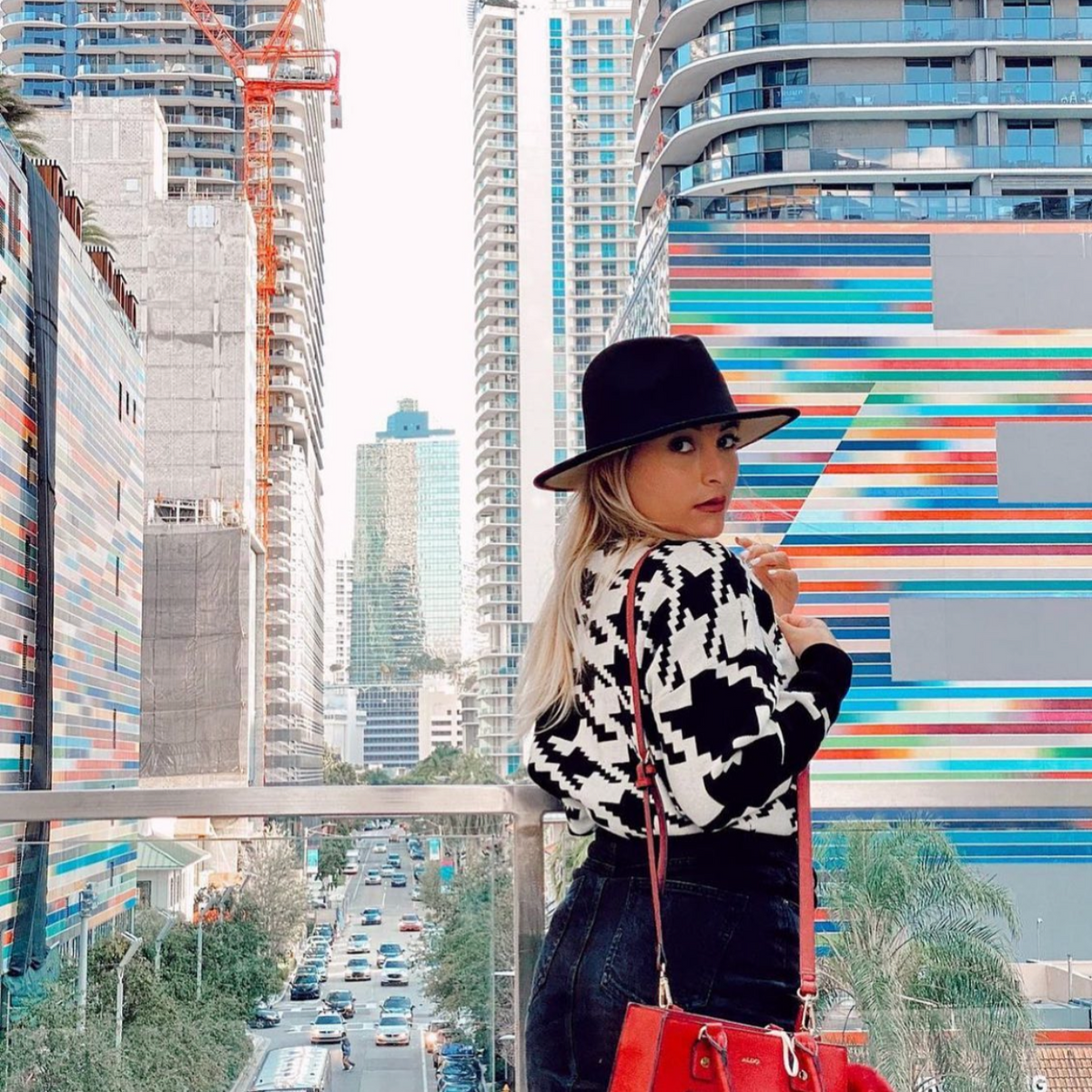 Woman wearing Zair two-tone fedora on colorful outdoor stairs.