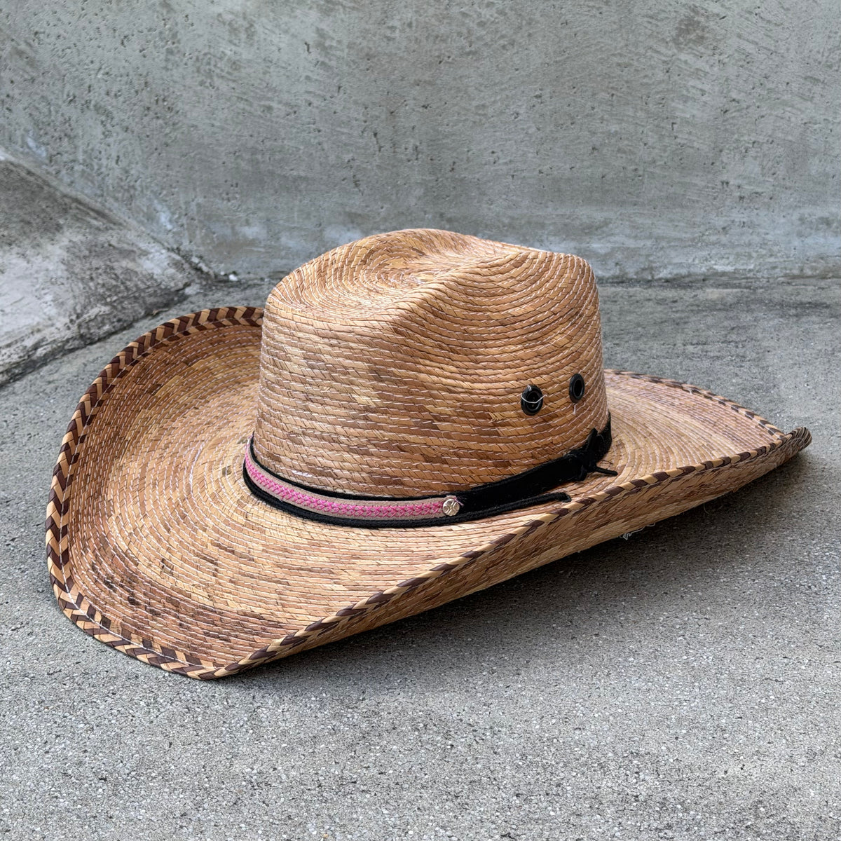 Rodrigo burnt palm cowboy hat with decorative woven brim edge, dark band and metal eyelets, three-quarter view.