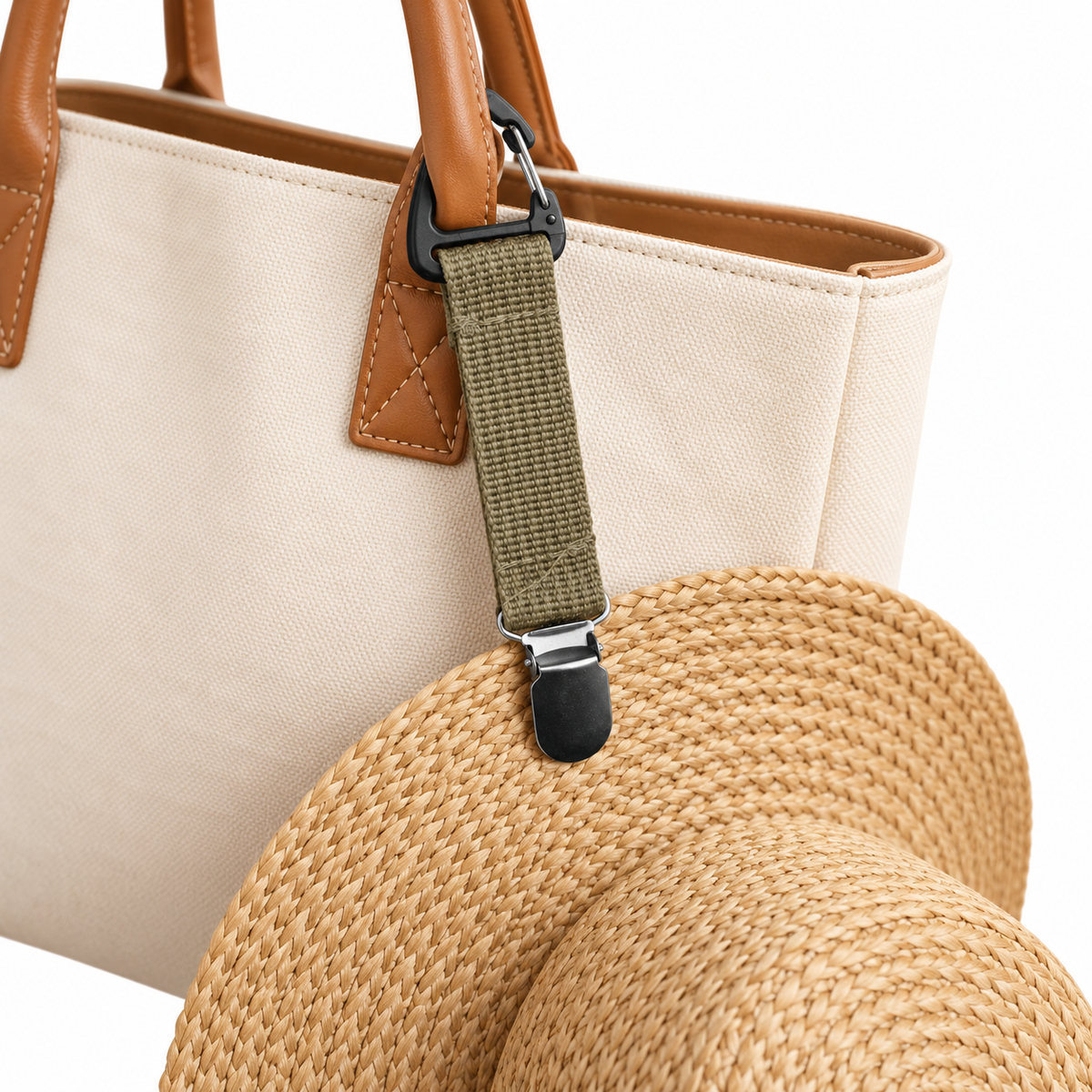 Illustration of an olive Ave hat clip attached to a canvas handbag handle and holding the brim of a straw hat.