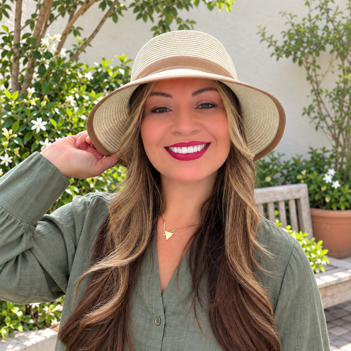 Model wearing Catalina White bucket hat with beige trim in a garden courtyard, square image.