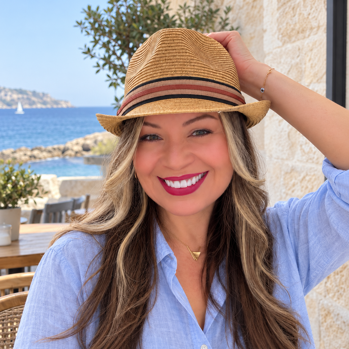 Woman wearing Fer tan striped-band fedora on a coastal terrace.