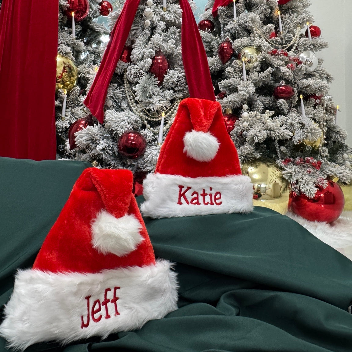 Jeff and Katie embroidered Santa hats with Christmas trees in the background