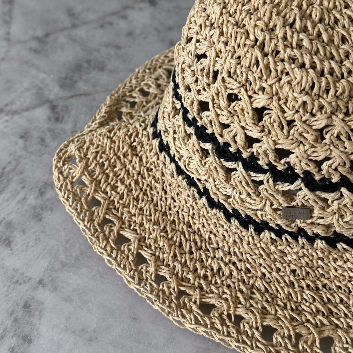 Close-up of Karina beige crochet hat showing black stripes and The American Hats pin