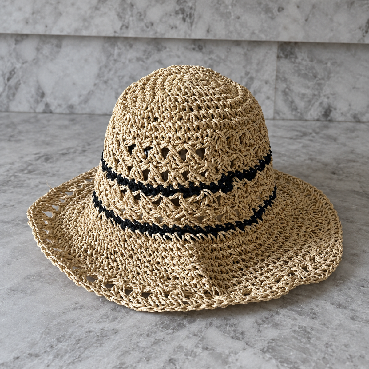 Karina beige crochet bucket hat with contrasting black stripes on a stone surface