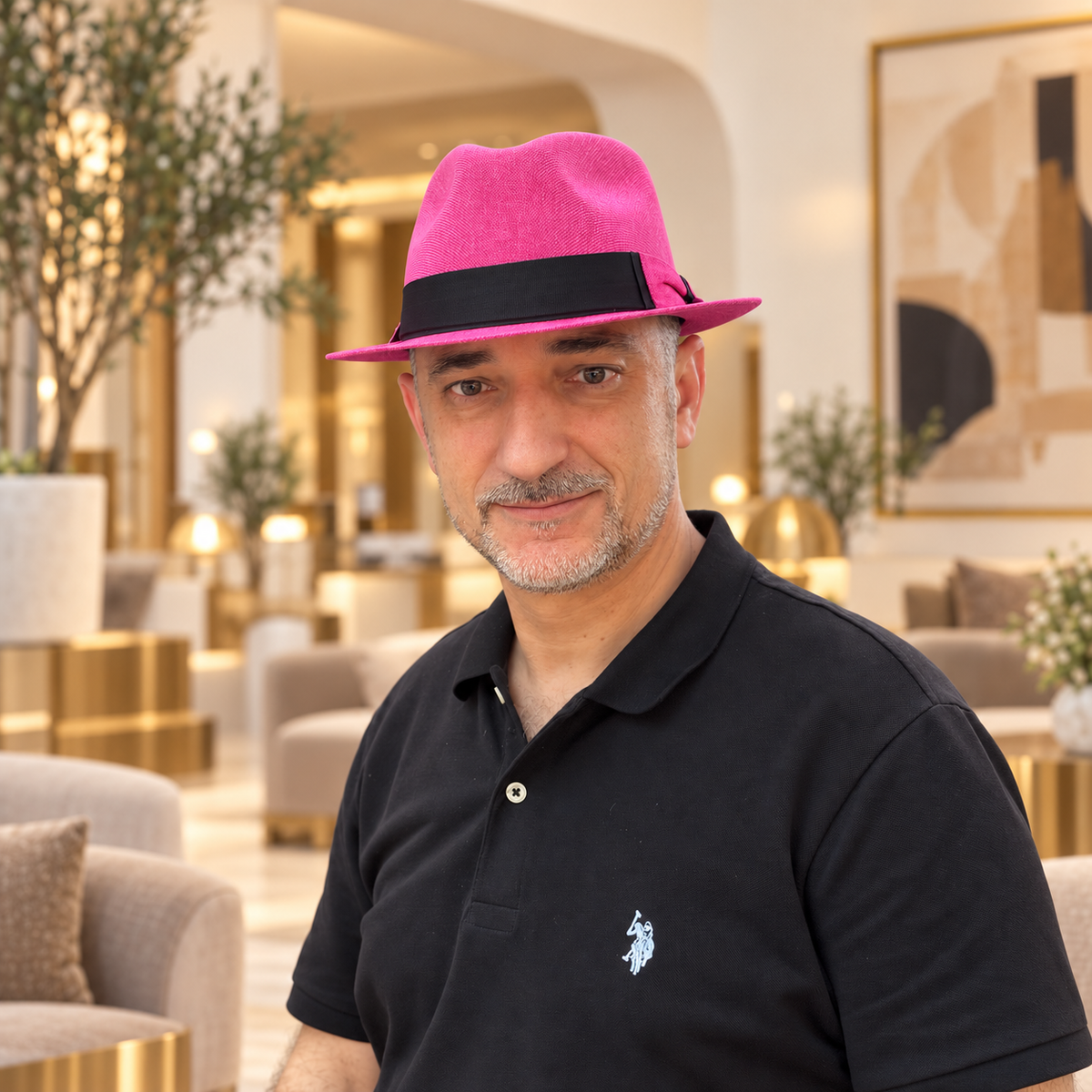 Man wearing Mia hot pink structured fedora with black band in an elegant indoor lobby
