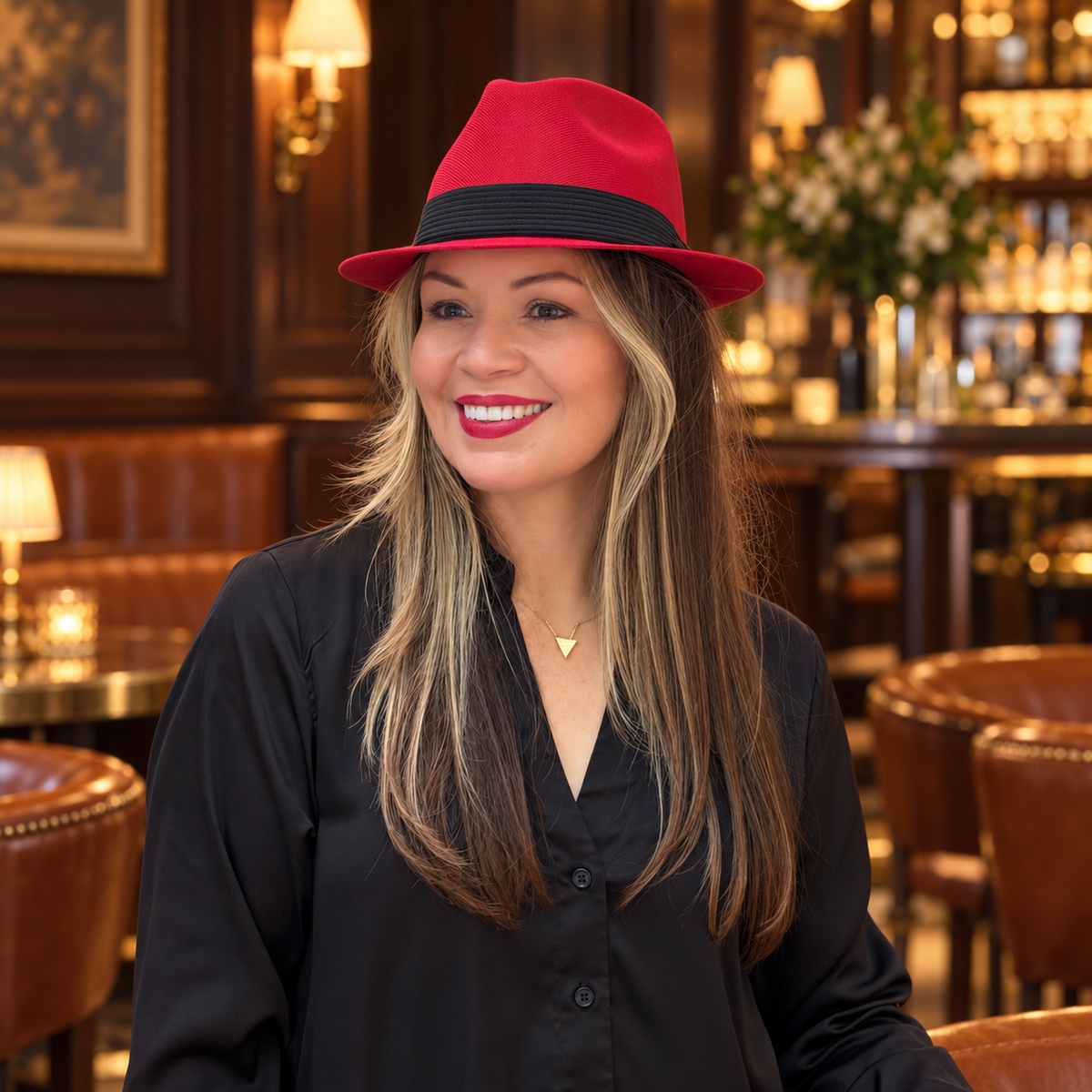 Woman wearing Mia red structured fedora with a black blouse at an indoor bar.