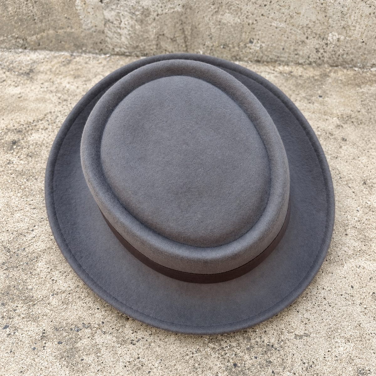 Top view of Monte Carlo gray wool hat showing recessed flat crown on a textured stone background