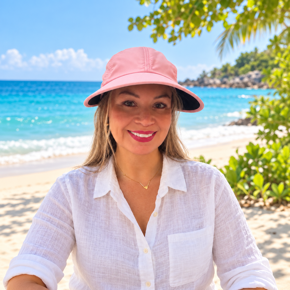 Woman wearing the pink Pia visor hat with loose hair at the beach.