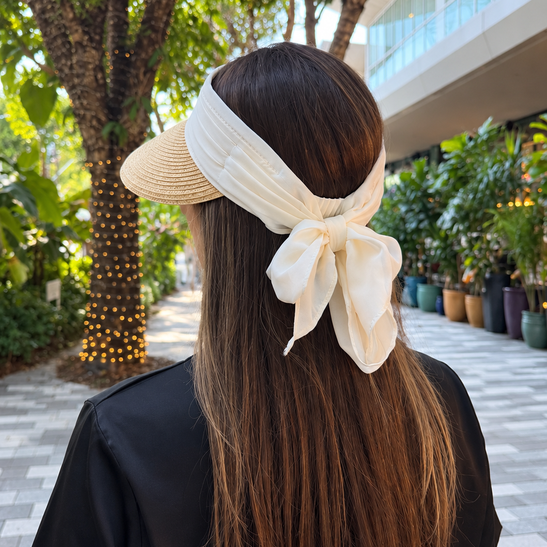 Rear view of Vero natural sun visor showing its ivory fabric band and chiffon bow on a woman with long hair.
