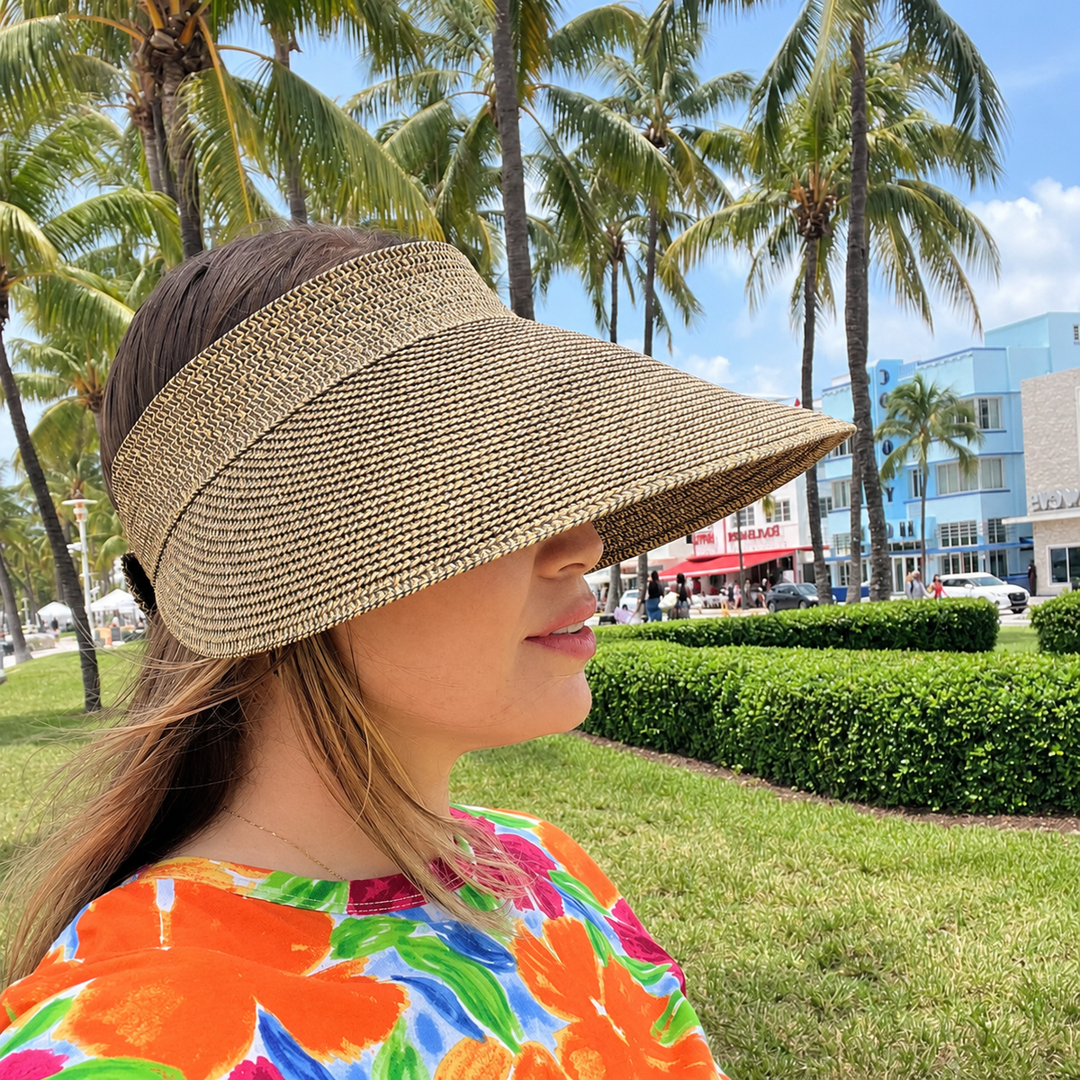 Woman wearing the mixed brown Zara extra-wide brim sun visor outdoors beneath palm trees.