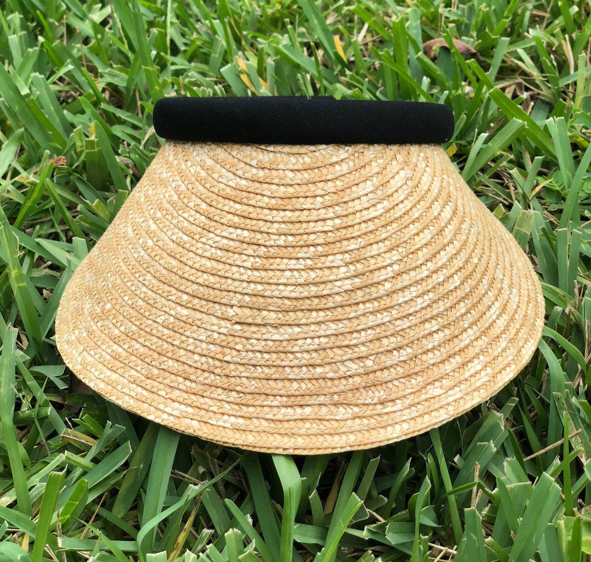 Front view of the Bela natural woven visor on grass