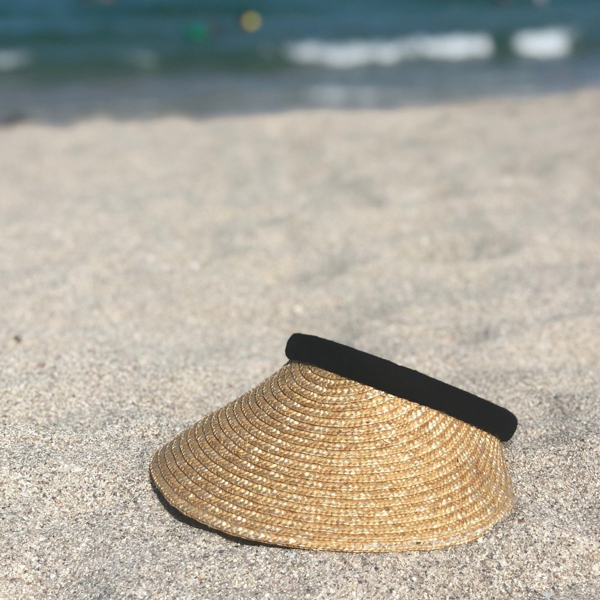 Bela natural visor with a black band photographed on a sandy beach