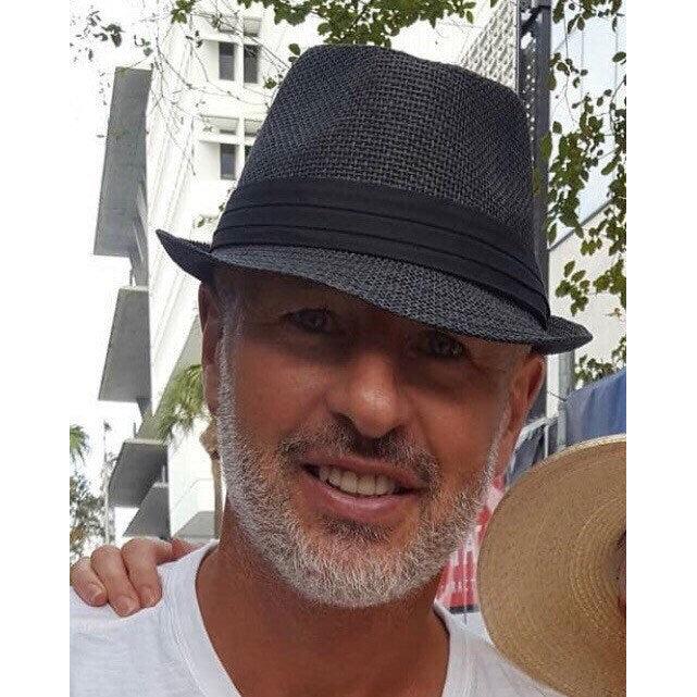Man wearing Raven black short-brim fedora outdoors.